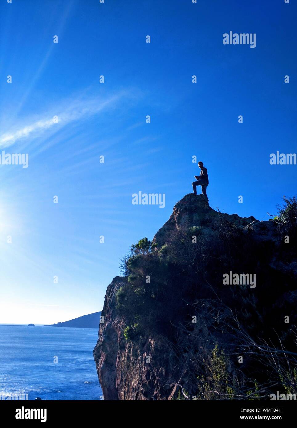 Man Standing On Beach Cliff Against Blue Sky Stock Photo