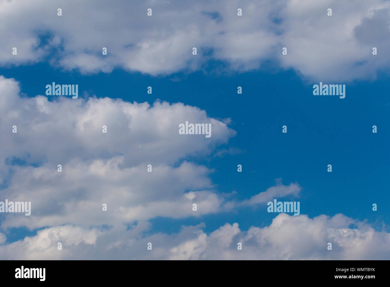 Slightly grey Cumulus clouds in a bright blue sky Stock Photo