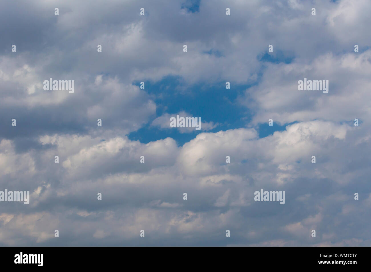 Slightly grey Cumulus clouds in a bright blue sky Stock Photo