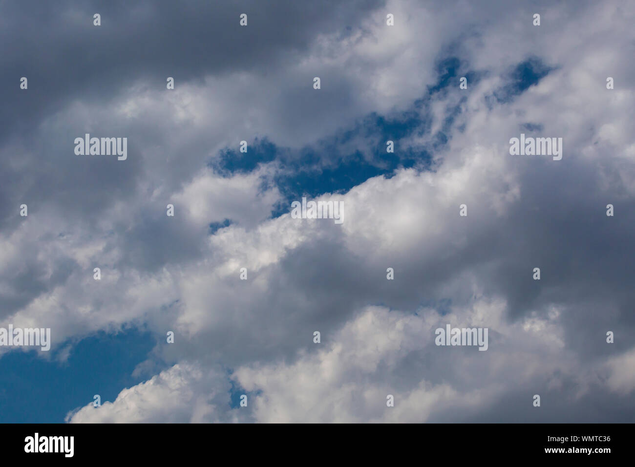 Slightly grey Cumulus clouds in a bright blue sky Stock Photo