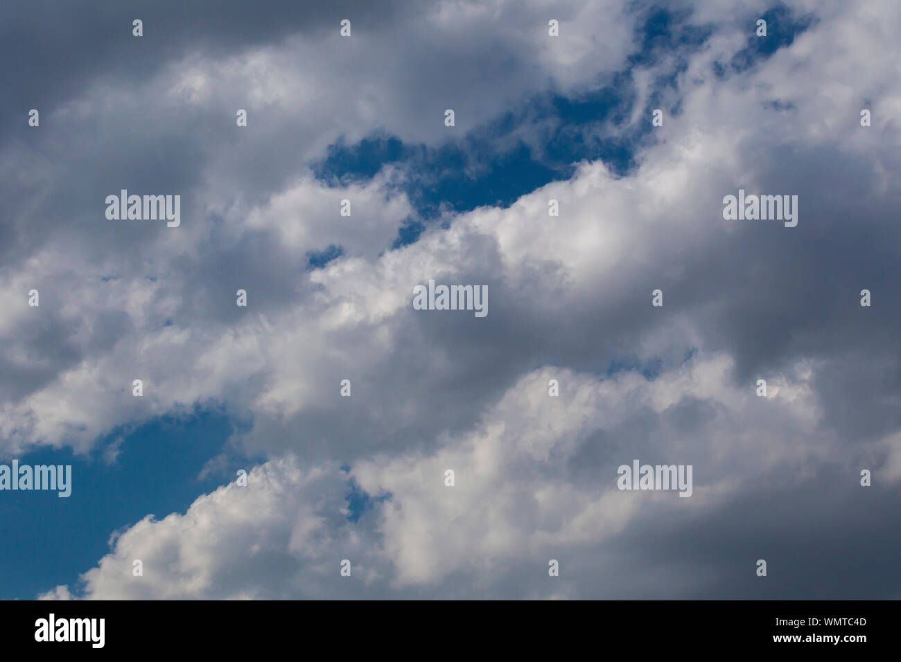Slightly grey Cumulus clouds in a bright blue sky Stock Photo
