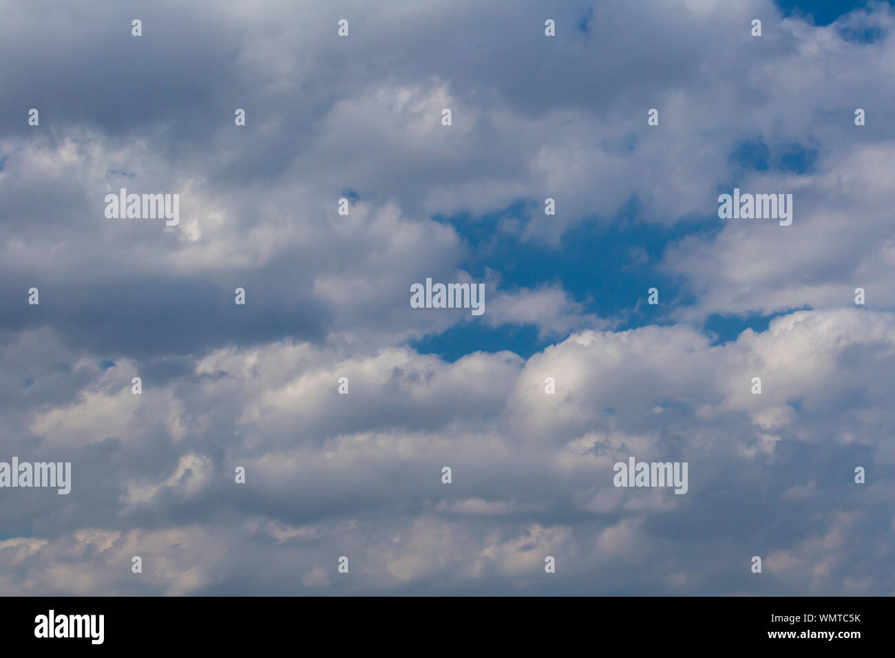 Slightly grey Cumulus clouds in a bright blue sky Stock Photo