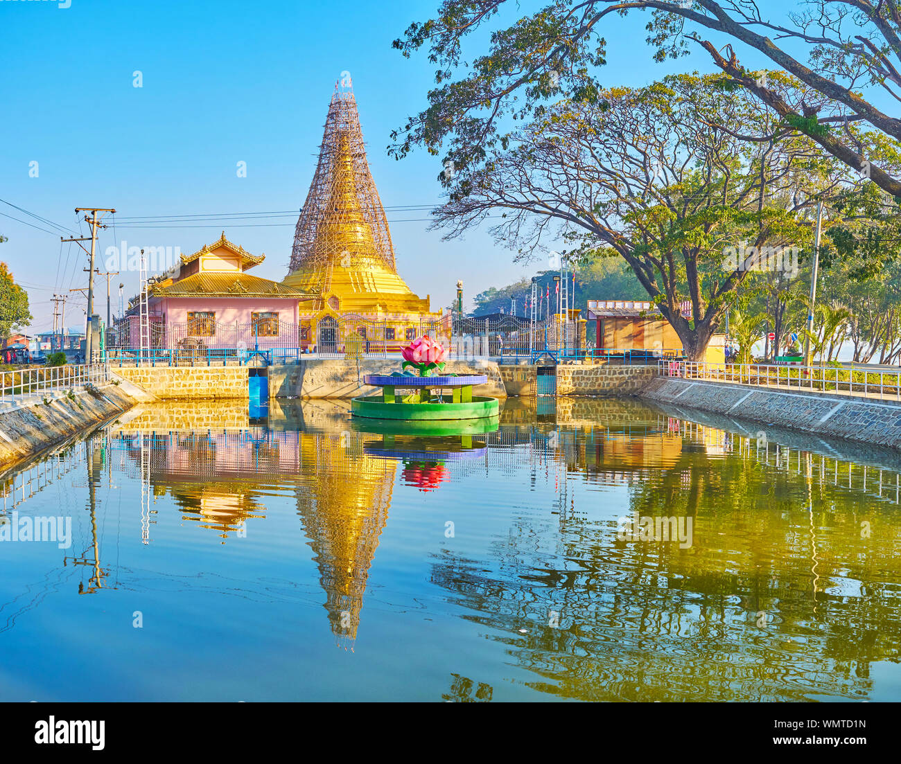 Walk around the lotus fountain and watch scenic Shwe Baww Di Pagodaand its reflection on rippled water surface, Nyaungshwe, Myanmar Stock Photo