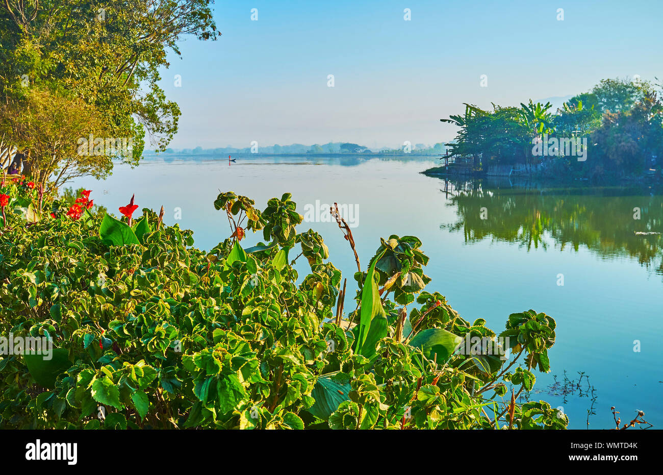 Relax on the bank of Tharzi pond and watch its clear surface, surrounded by lush greenery, Nyaungshwe, Myanmar Stock Photo