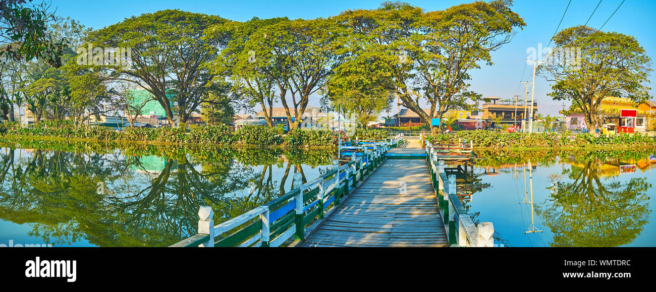 Panorama of Tharzi pond with old wooden bridge, connecting its banks, covered with spread trees, Nyaungshwe, Myanmar Stock Photo