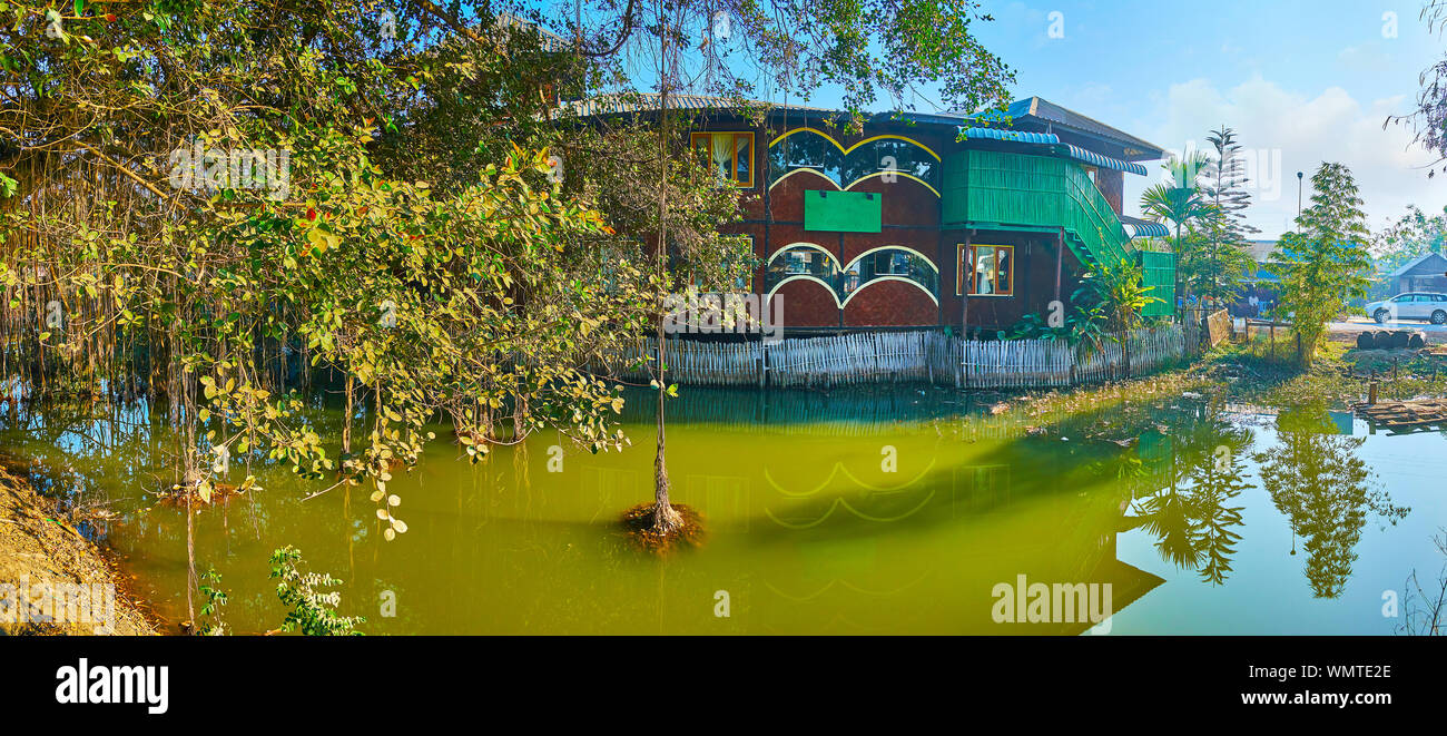 Panorama of Tharzi pond, spread banyan tree with aerial roots and old wooden stilt building of local hotel, Nyaungshwe, Myanmar Stock Photo