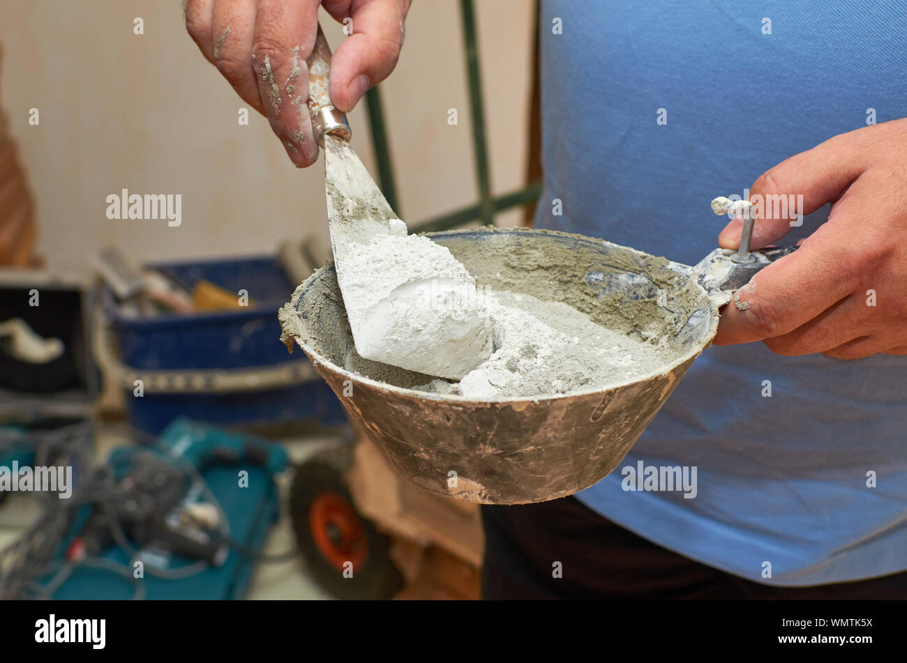 Hands holding scraper and plasterer's scoop with gypsum powder while ...