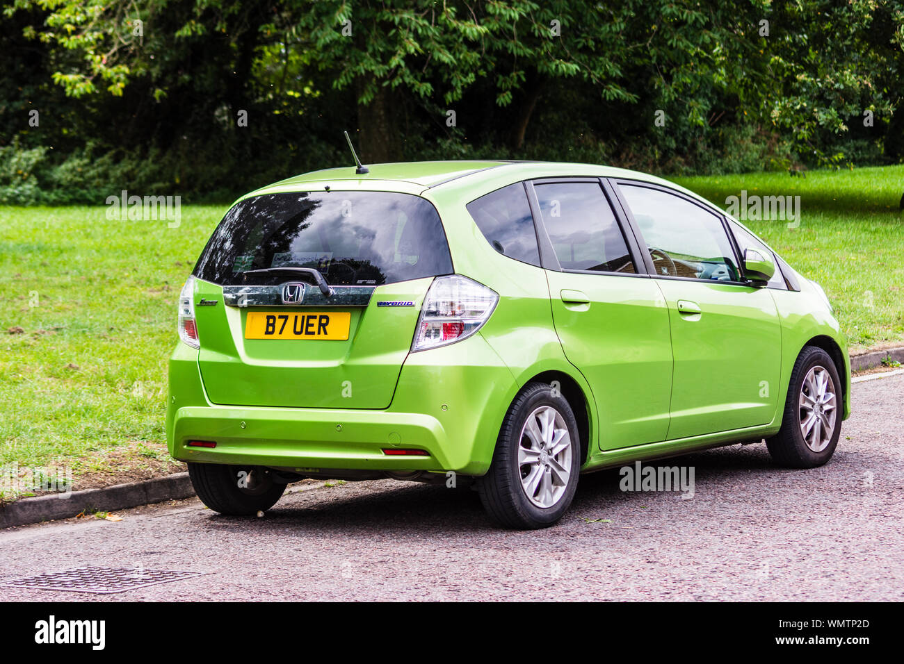 A Honda Jazz Hybrid car in the colour green, parked at the side of the road by a grass verge, seen in rear 3/4 view Stock Photo