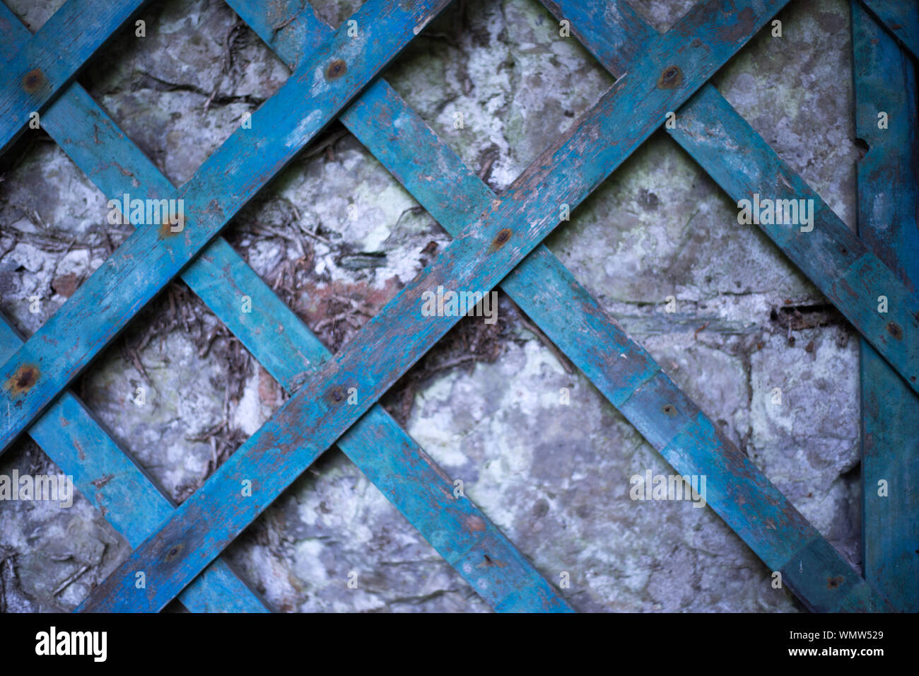 Vintage blue painted wooden lattice on an old stone wall Stock Photo