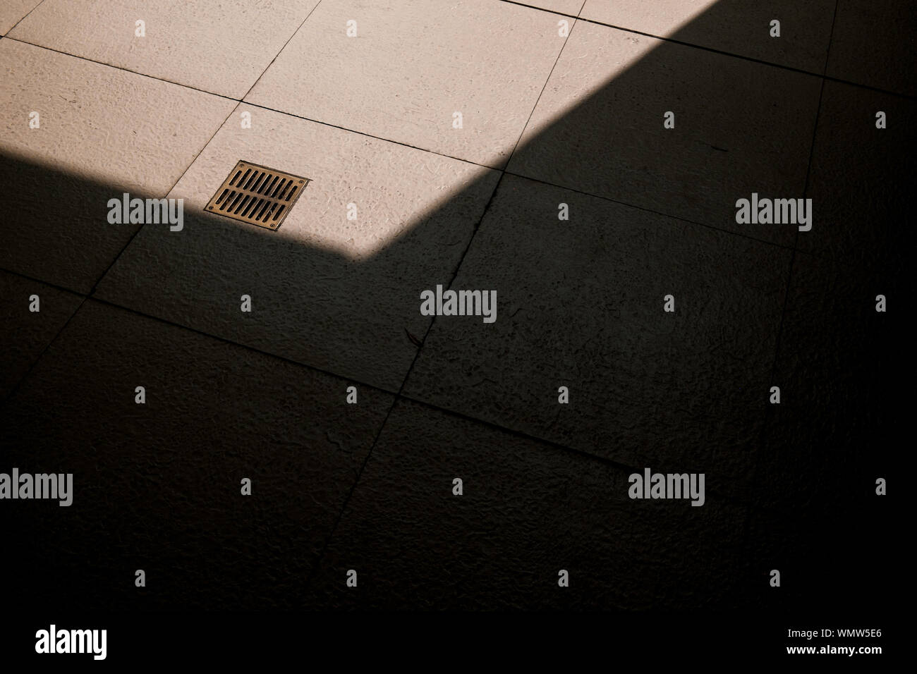 High Angle View Of Metal Grid Cover On Manhole Over Tiled Floor Stock Photo