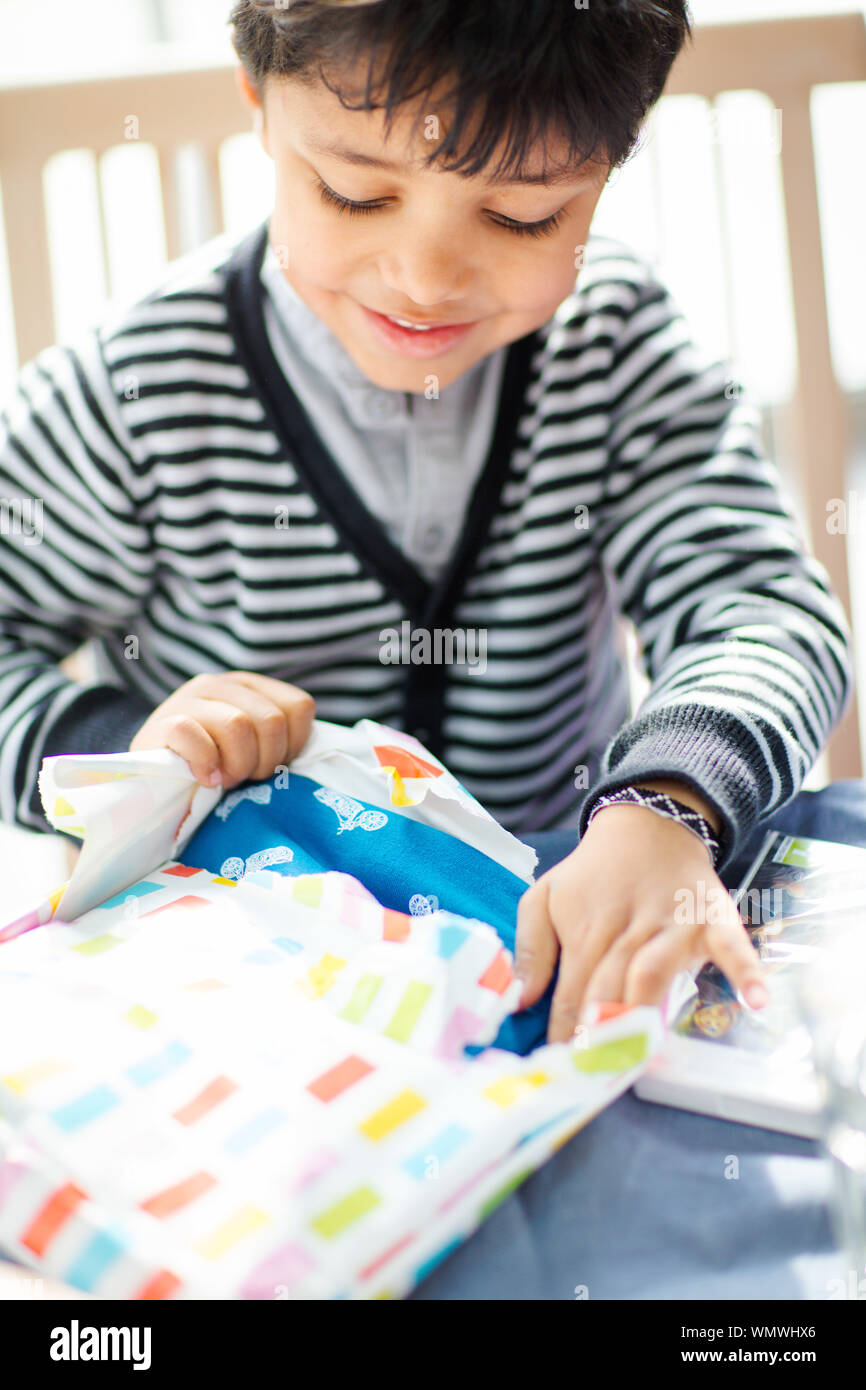 Happy Boy Tearing Gift Paper At Home Stock Photo