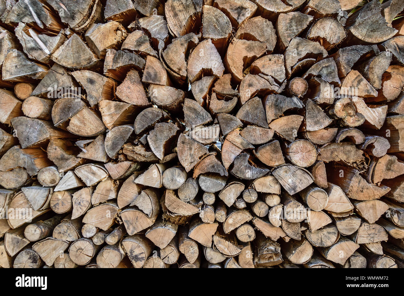 Stack of sawn tree logs detail. Stacked pile of wood logs stored for winter as firewood. Lumber industry. Wooden textured background Stock Photo
