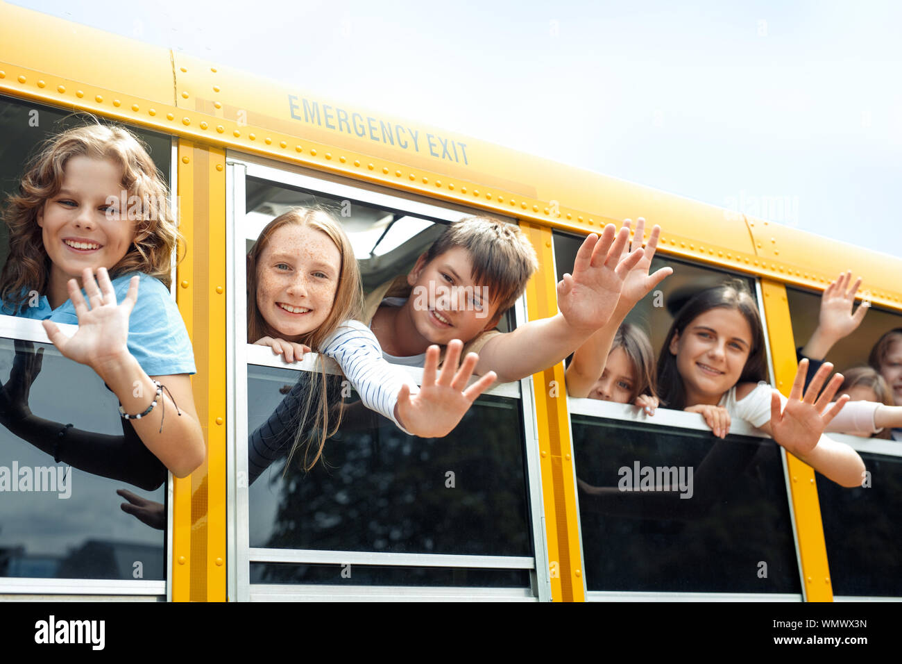 Group of children classmates going to school by bus leaning out of the ...