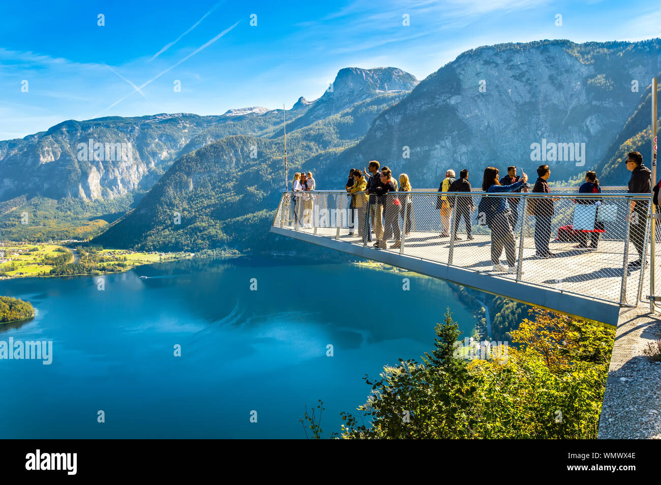 Hallstatt, Austria - OCT 2018: Tourists take photos and enjoy the view of the mountains and lake Hallstatter See from the World Heritage View Point. Stock Photo