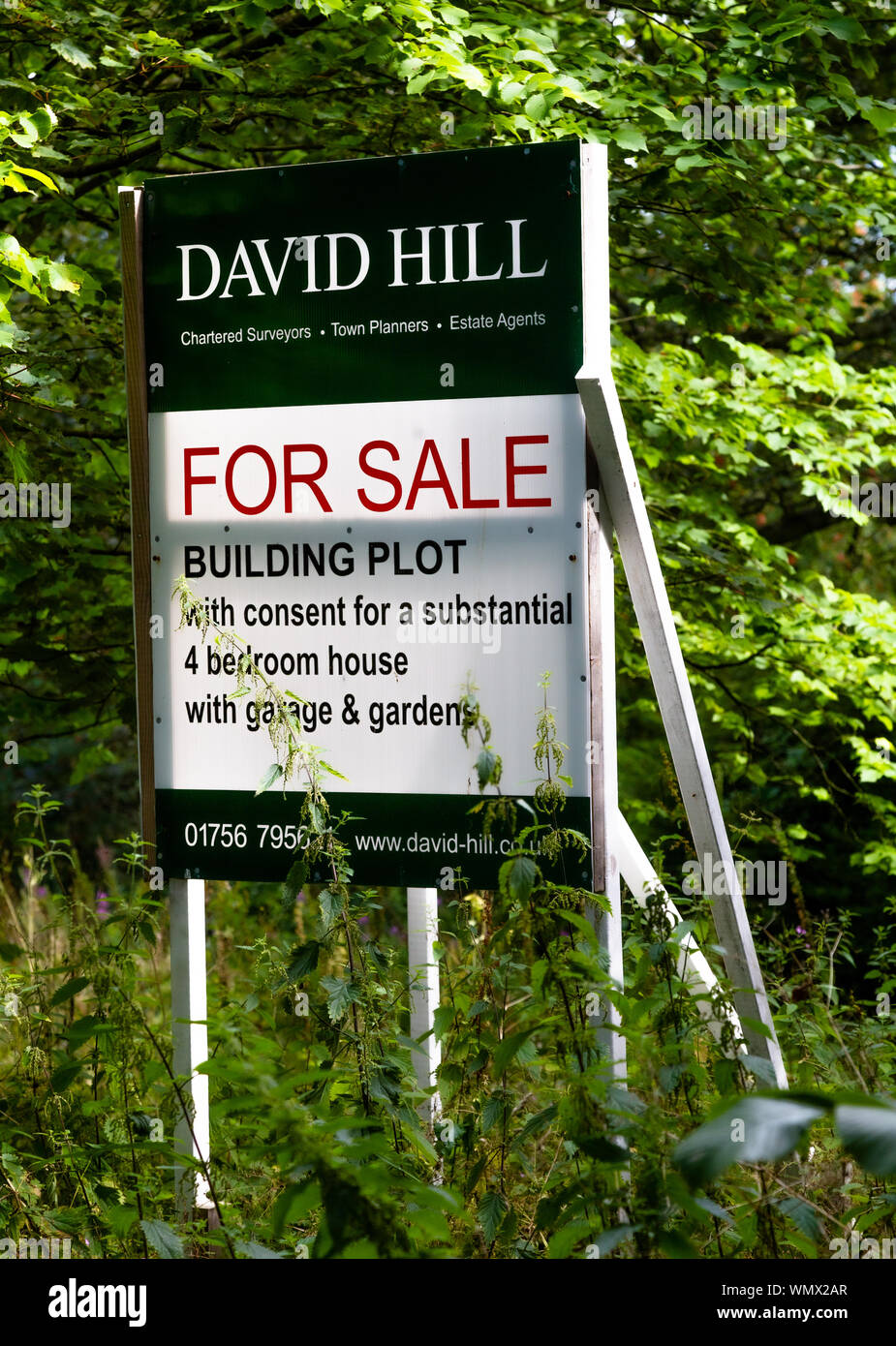 A for sale sign showing the sale of a plot of land with planning permission for building a house. Stock Photo