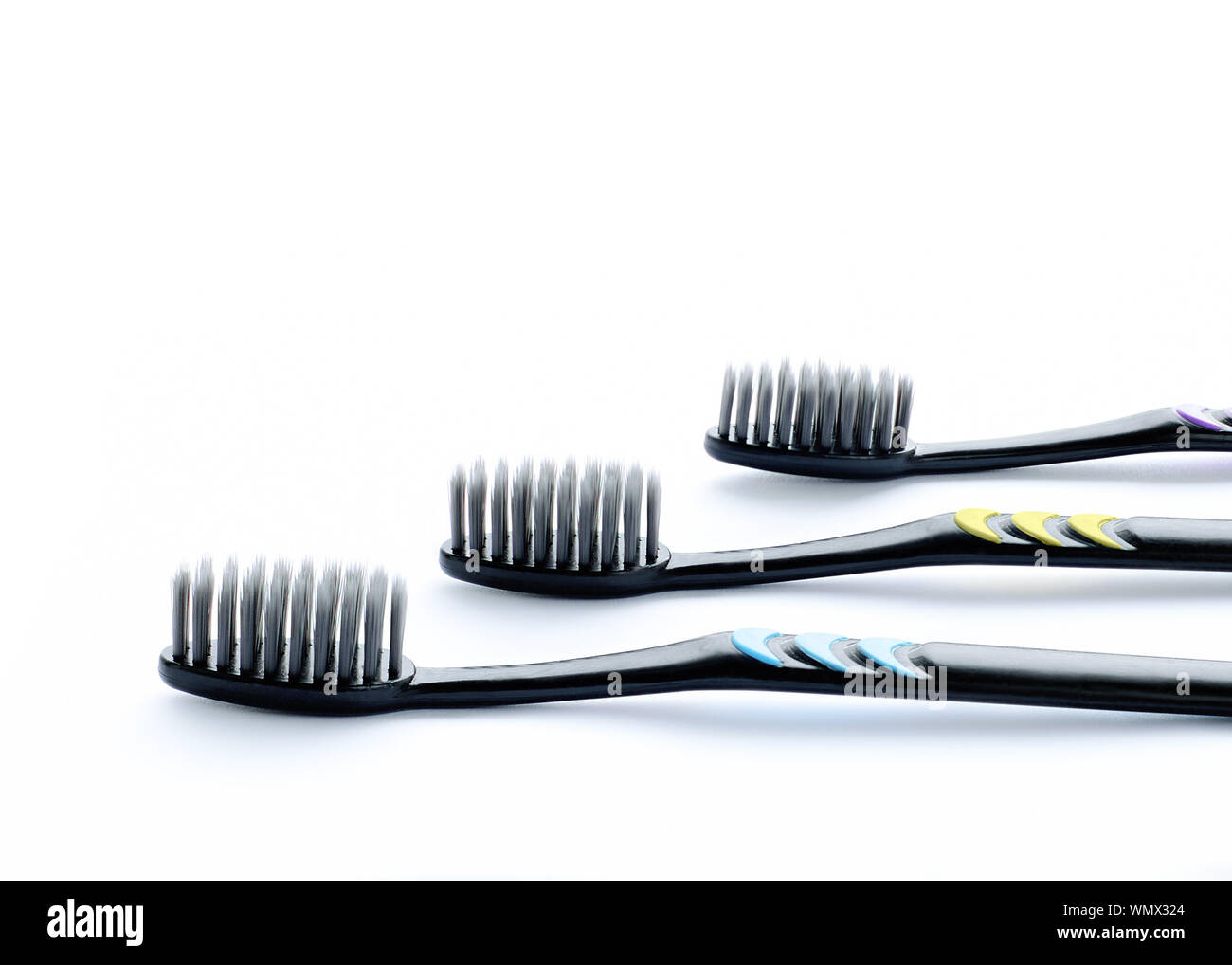 Three black toothbrushes with large carbon bristles. White background