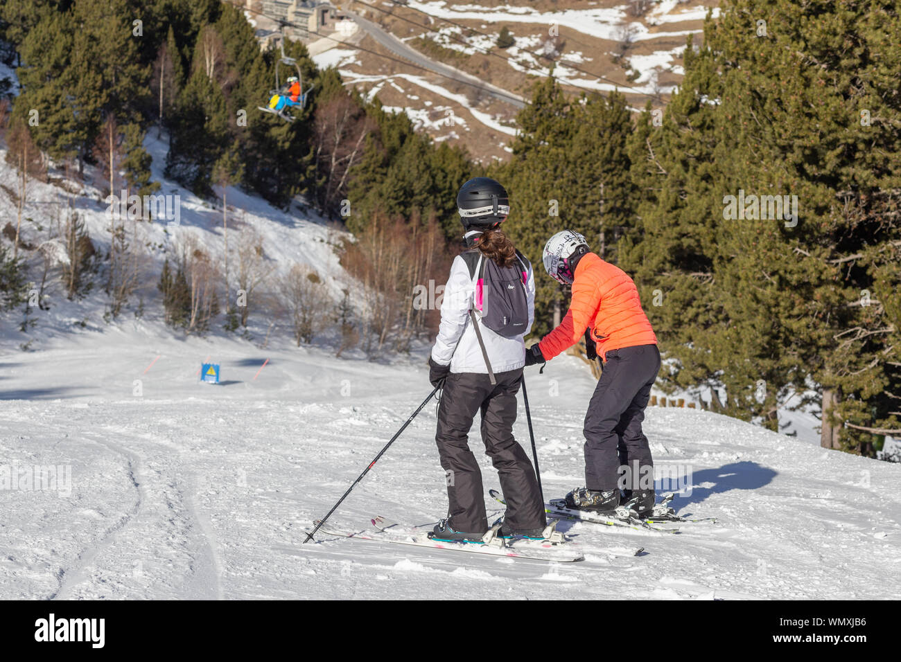 PYRENEES, ANDORRA - FEBRUARY 12, 2019: Two skiers stand at the beginning of the ski slope and look down. Pyrenees, Andorra, winter sunny day Stock Photo