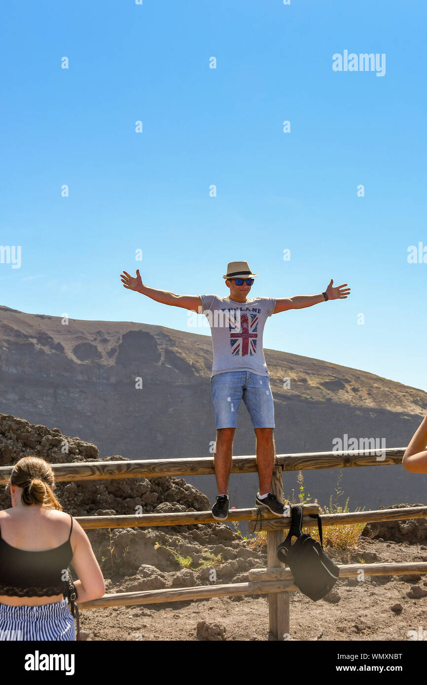 NAPLES, ITALY - AUGUST 2019: Person wearing England t shirt standing on the wooden fence which surrounds the crater at the summit of Mount Vesuvius Stock Photo