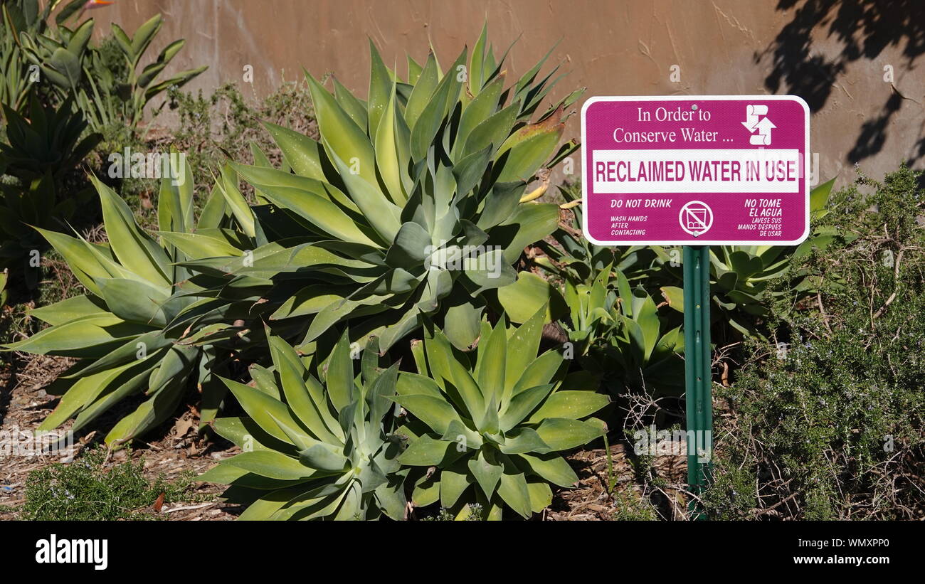 A sign warns people that reclaimed water is in use in the landscaping to conserve water Stock Photo