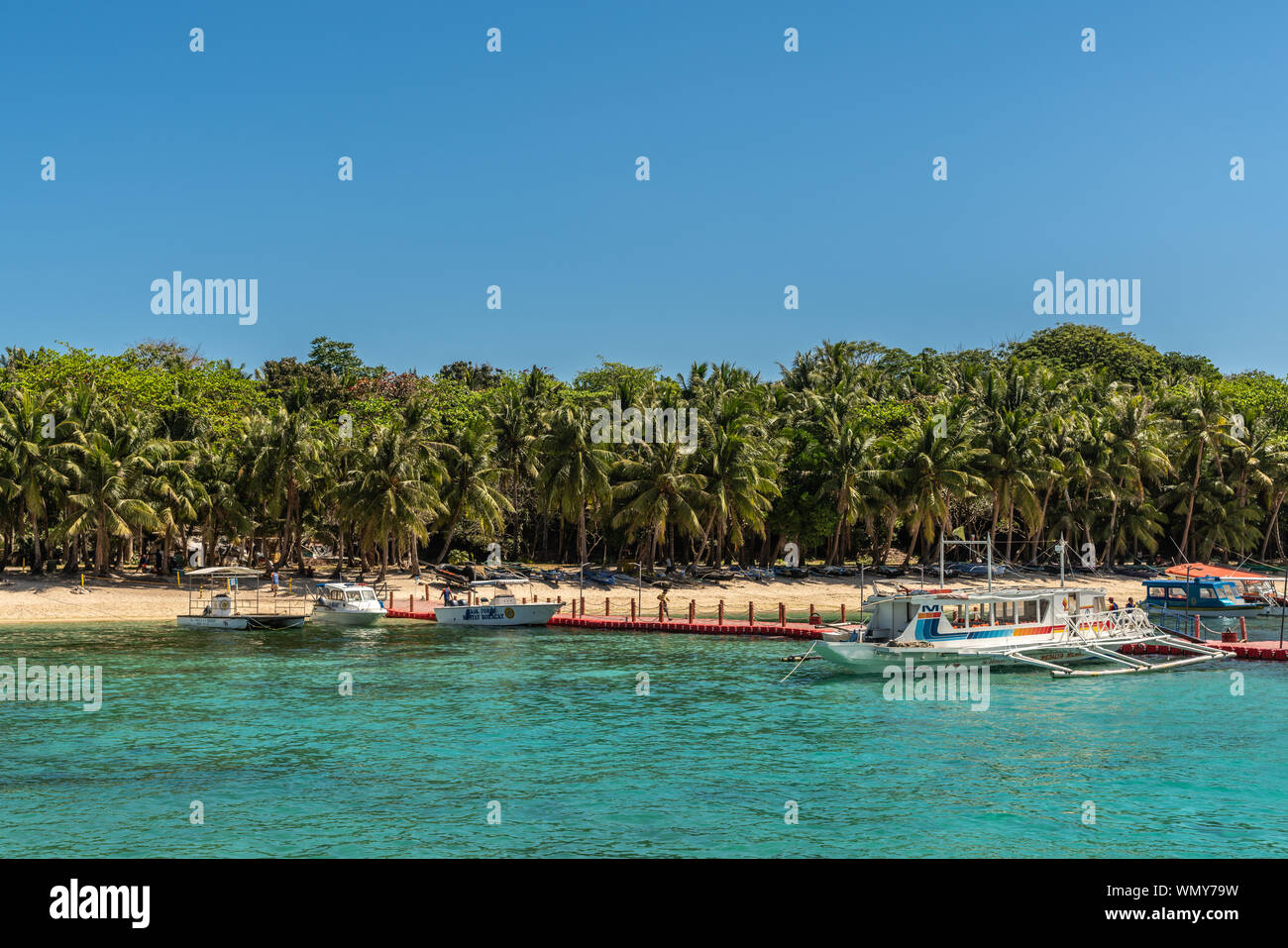 Manoc-Manoc, Boracay, Philippines - March 4, 2019: Cagban Jetty Port and floating pier with small outrigger tourist ferries vessels on azure sea, unde Stock Photo