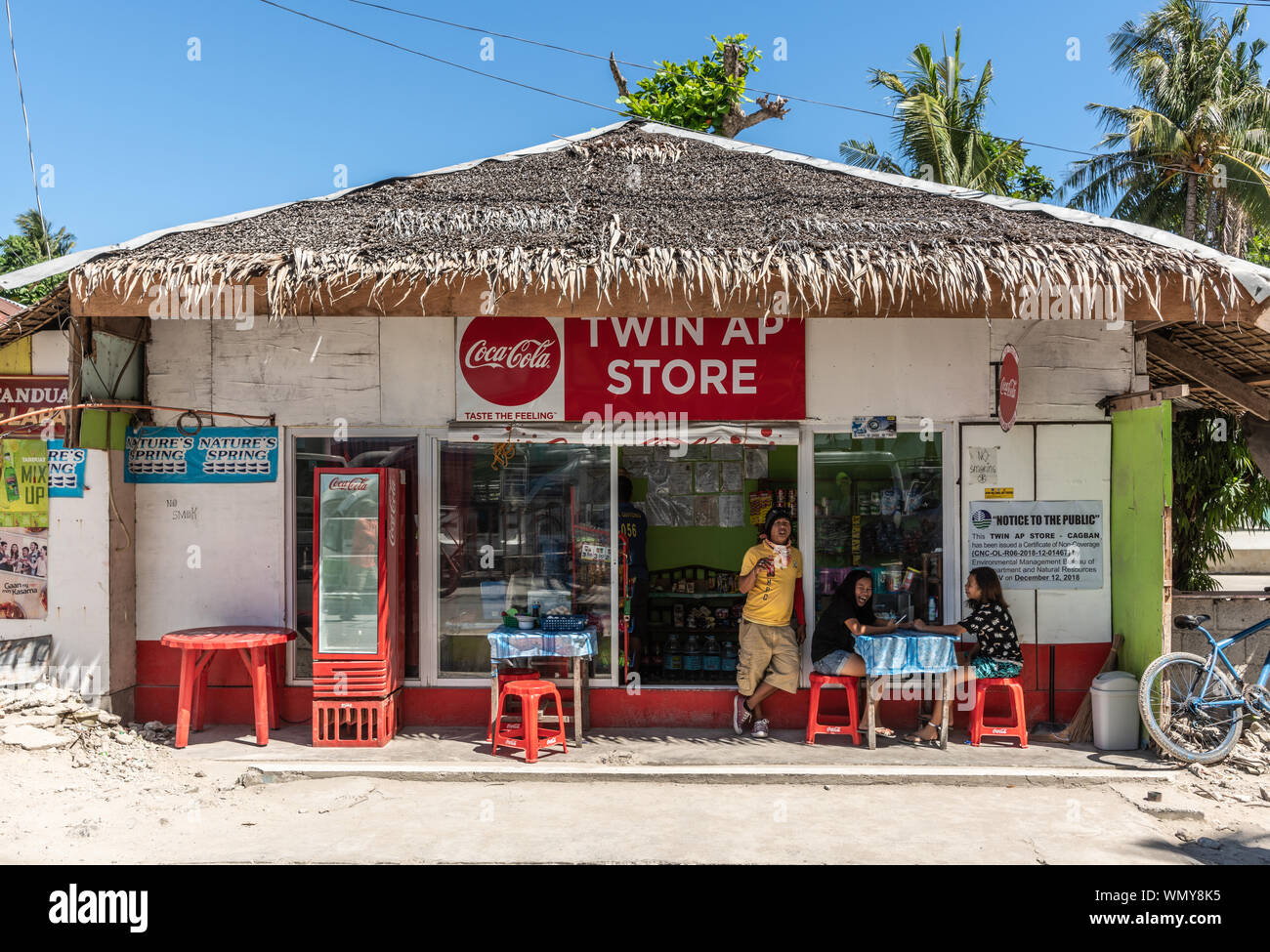 Manoc-Manoc, Boracay, Philippines - March 4, 2019: Twin Ap store is fast food and drink roadside hut with clients in front, straw roof, red tools, blu Stock Photo