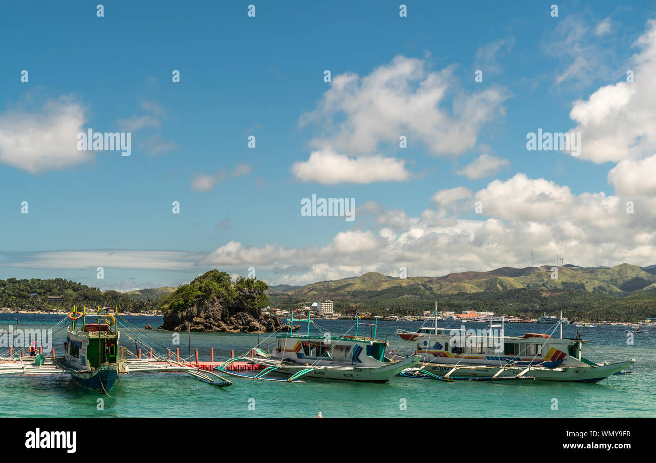 Manoc-Manoc, Boracay, Philippines - March 4, 2019: Cagban Jetty Port and floating pier with three small outrigger tourist ferries vessels on azure sea Stock Photo