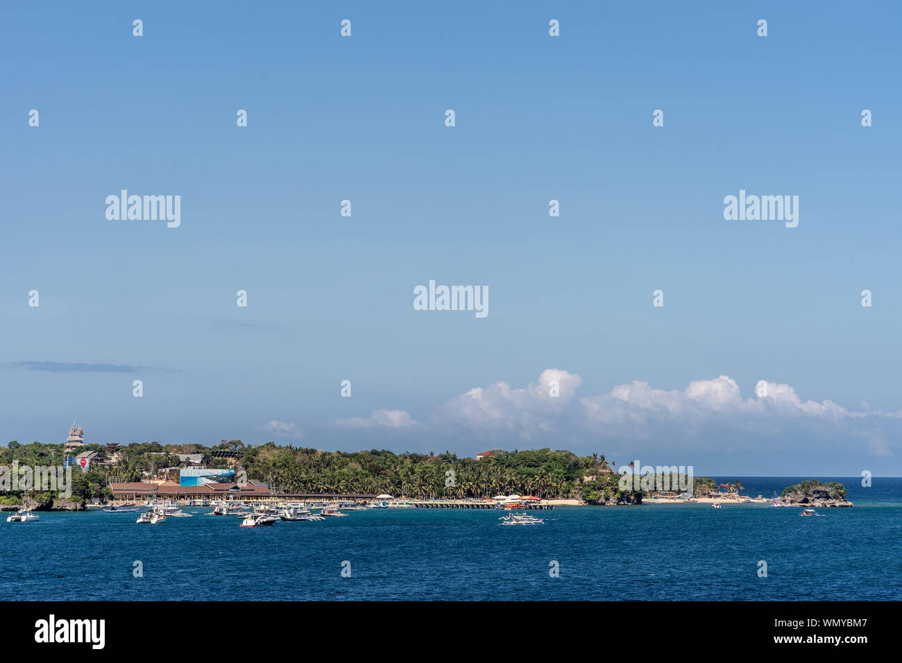 Manoc-Manoc, Boracay, Philippines - March 4, 2019: Wide shot from sea of Cagban Jetty Port with tens of small boats. Dark blue see in front, green ban Stock Photo
