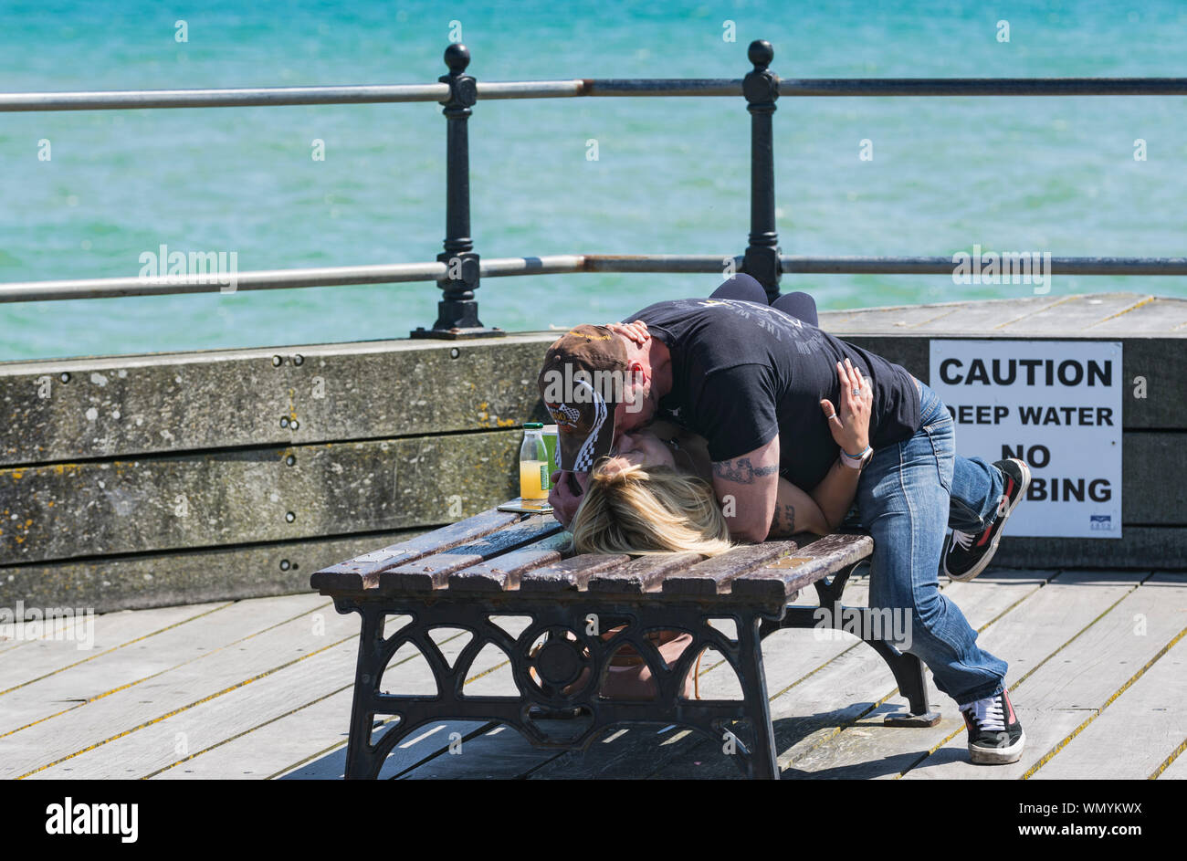 A couple enjoy a cheeky kiss in public on a hot day in Summer in the UK. Stock Photo