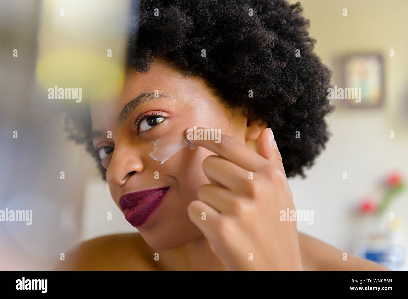 Young woman applying moisturizer to her face Stock Photo