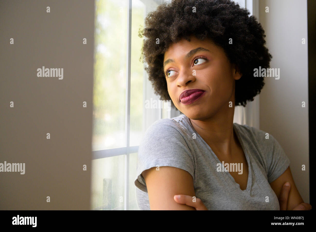 Young woman wearing lipstick by window Stock Photo