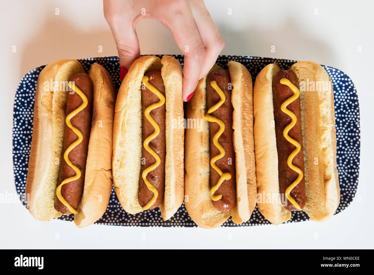 Woman's hand taking hot dog off of tray Stock Photo