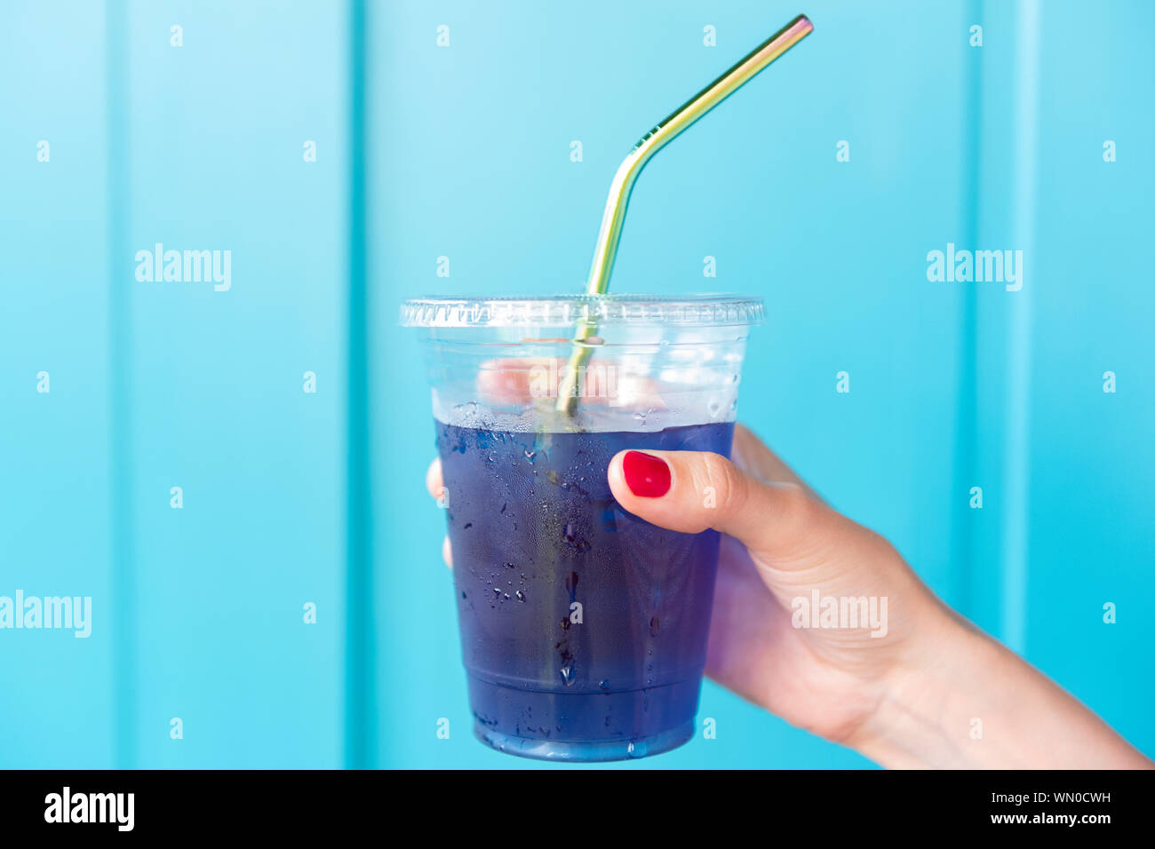 Woman holding blue drink in plastic cup with metal straw Stock Photo