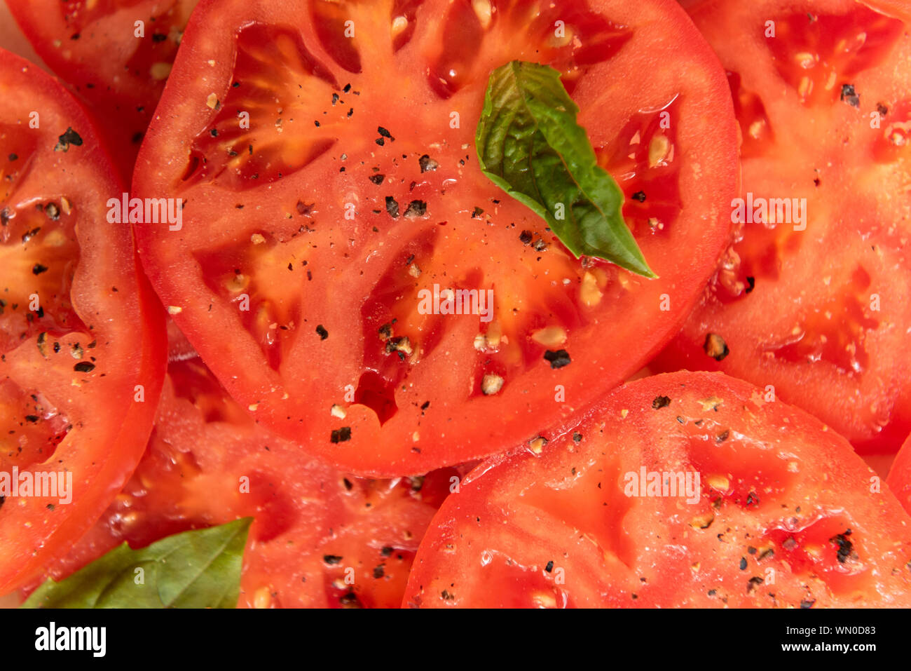 Sliced tomatoes with basil and pepper Stock Photo