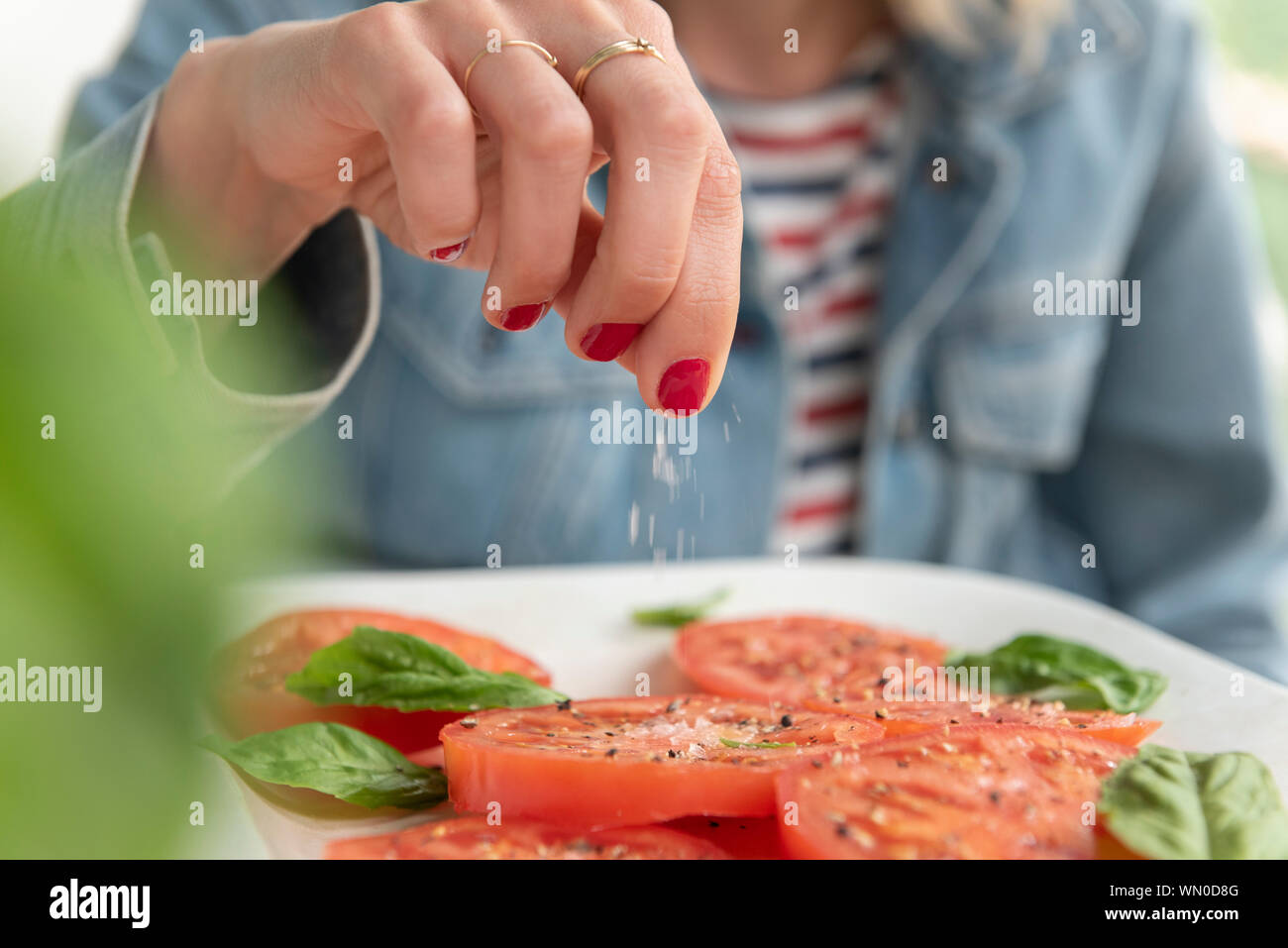 Woman sprinkling salt on tomatoes Stock Photo