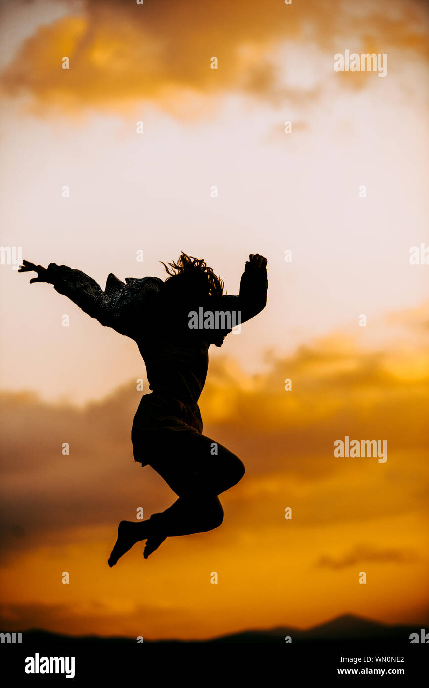 Silhouette of a beautiful female ballet dancer while jumping on sunset