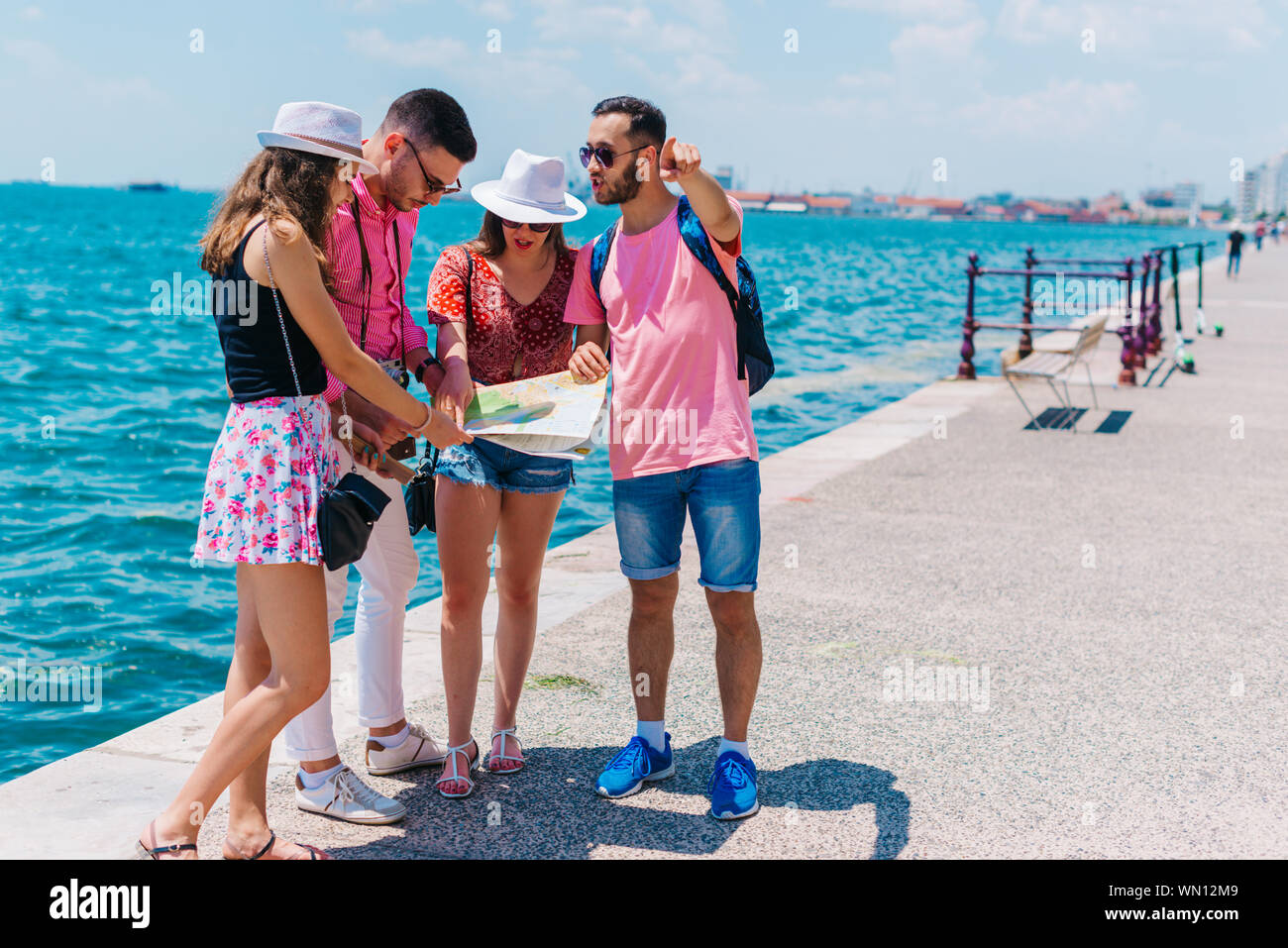 Young men and women smiling and trying to read map of tourist city ...