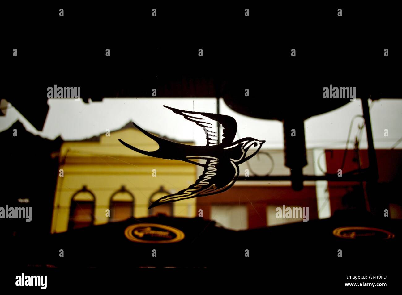 Close-up Of Bird Art On Window Glass Against Buildings Stock Photo