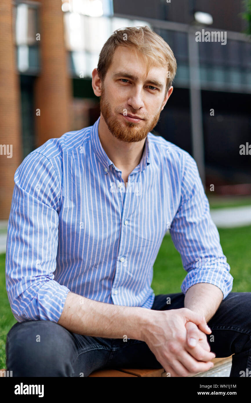Man wearing striped shirt sitting on bench Stock Photo