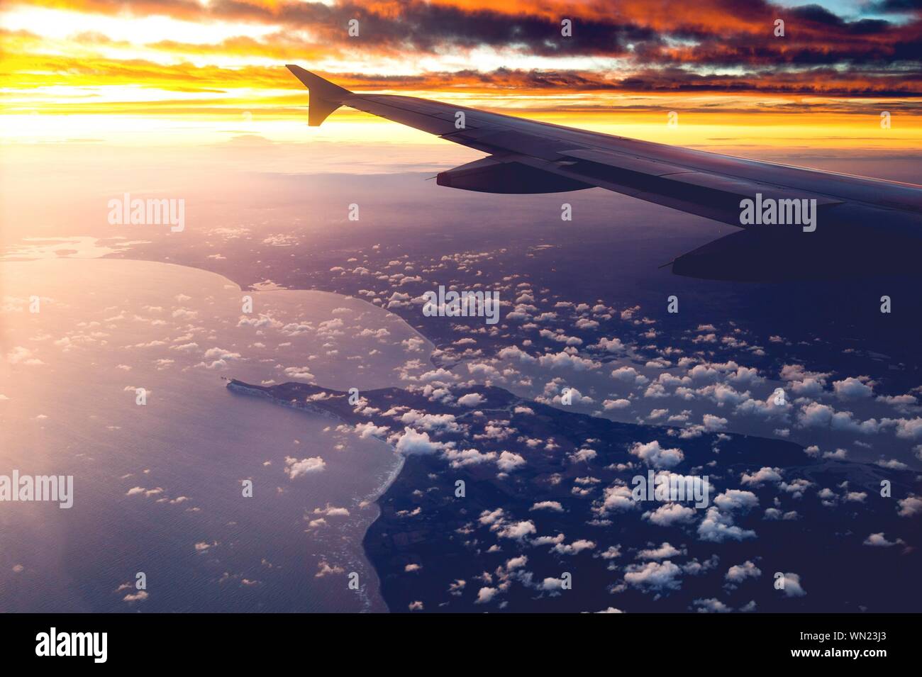 Wing of an airplane with clouds at sunset hi-res stock photography and ...