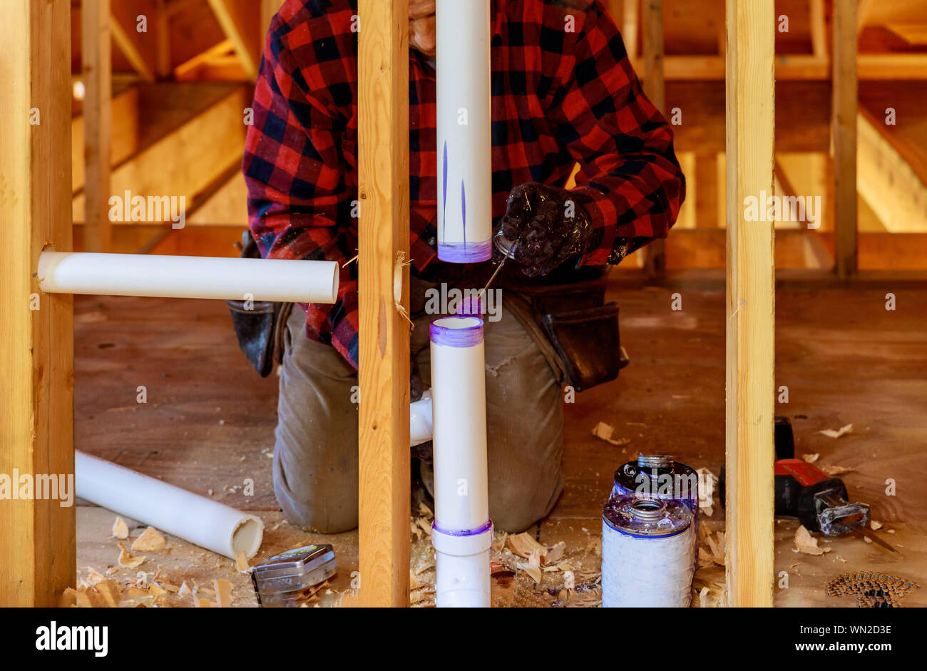A Plumber applying primer and glue a PVC pipe drain assembly in under