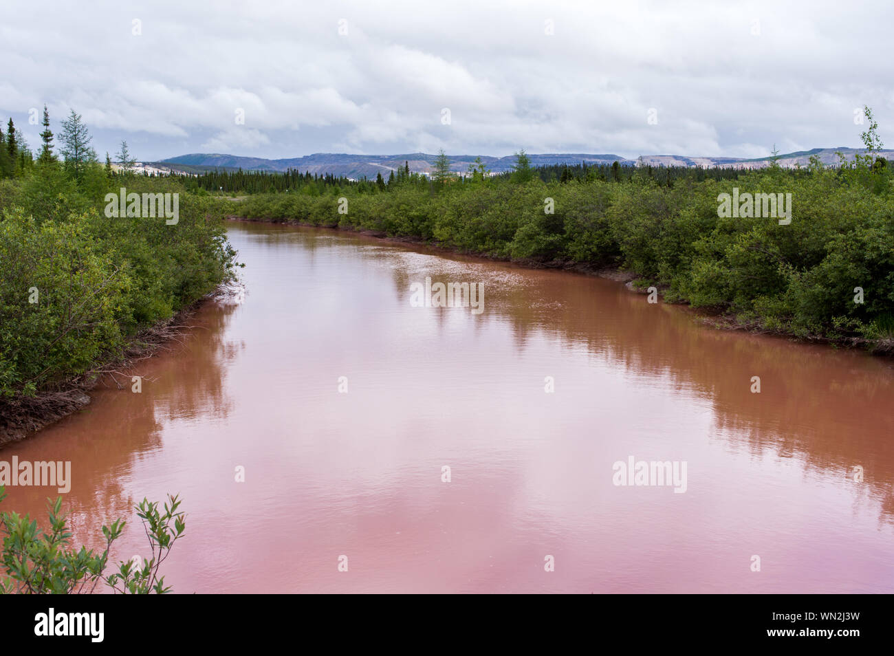 A river coloured red with iron oxide from an iron mine in northern Quebec Stock Photo