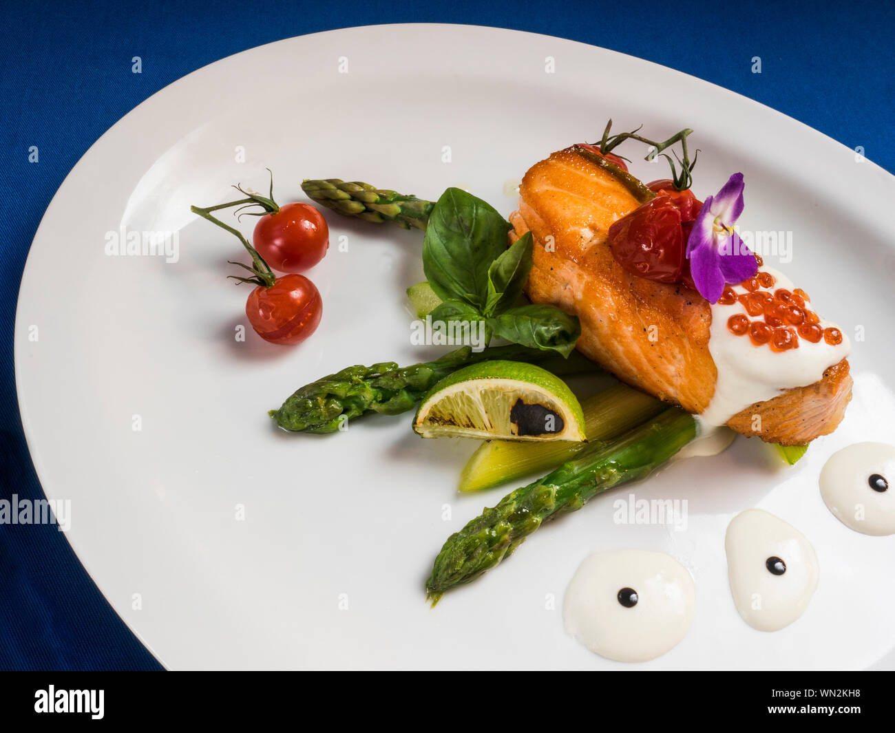 Fried Trout With Cream Sauce And Garnish Of Asparagus And Tomatoes Stock Photo