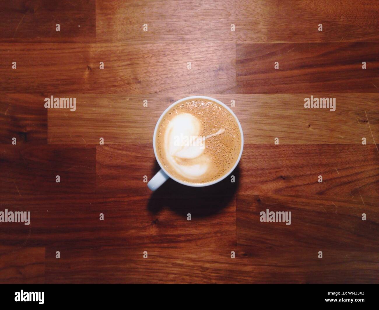 High Angle View Of Coffee With Froth Art On Hardwood Floor Stock Photo