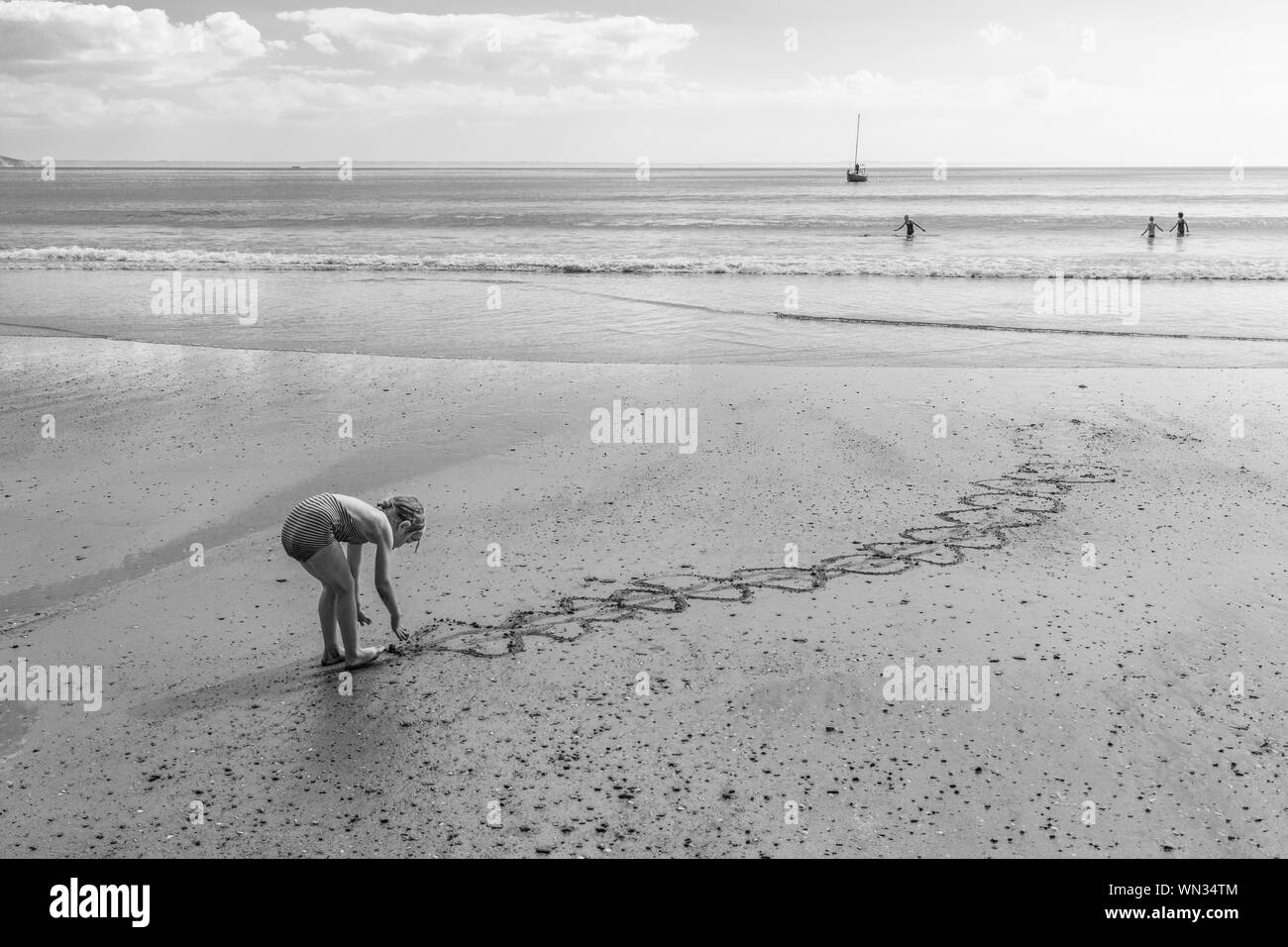Girl Making Design On Wet Sand At Beach Against Sky Stock Photo