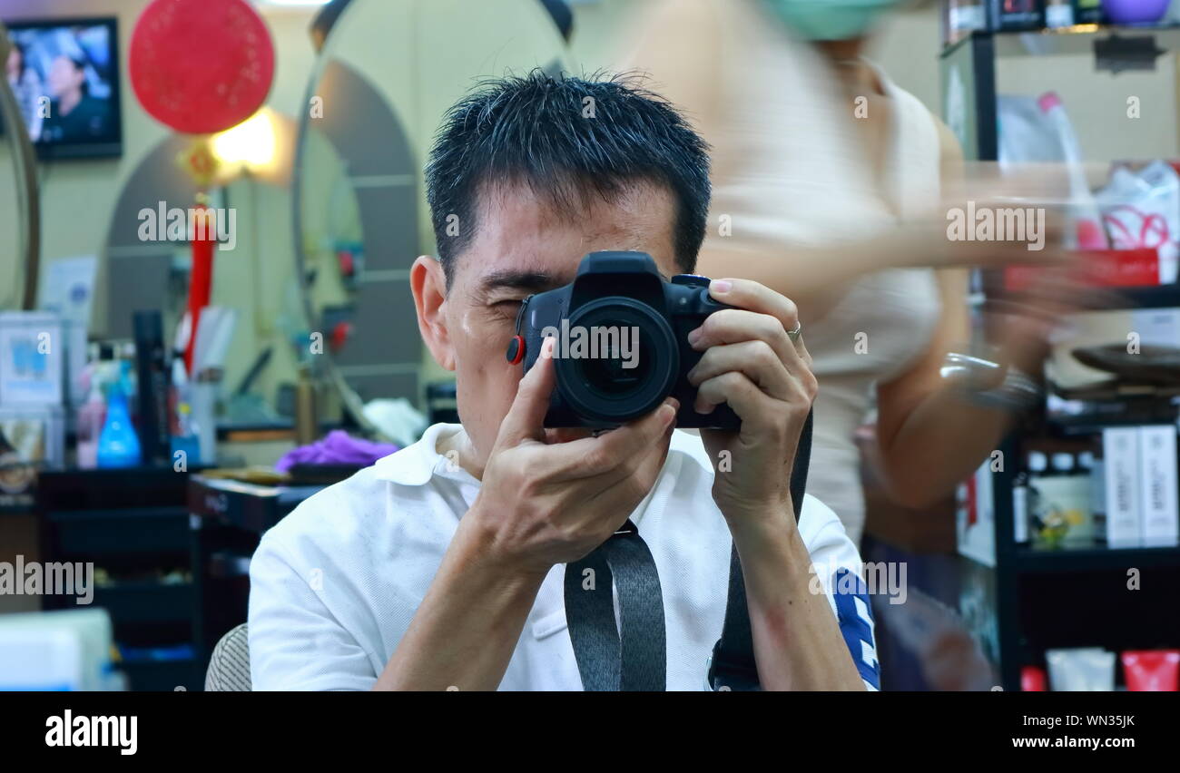 Closeup face in the mirror with DSLR camera while having a hair cut, self portrait Stock Photo