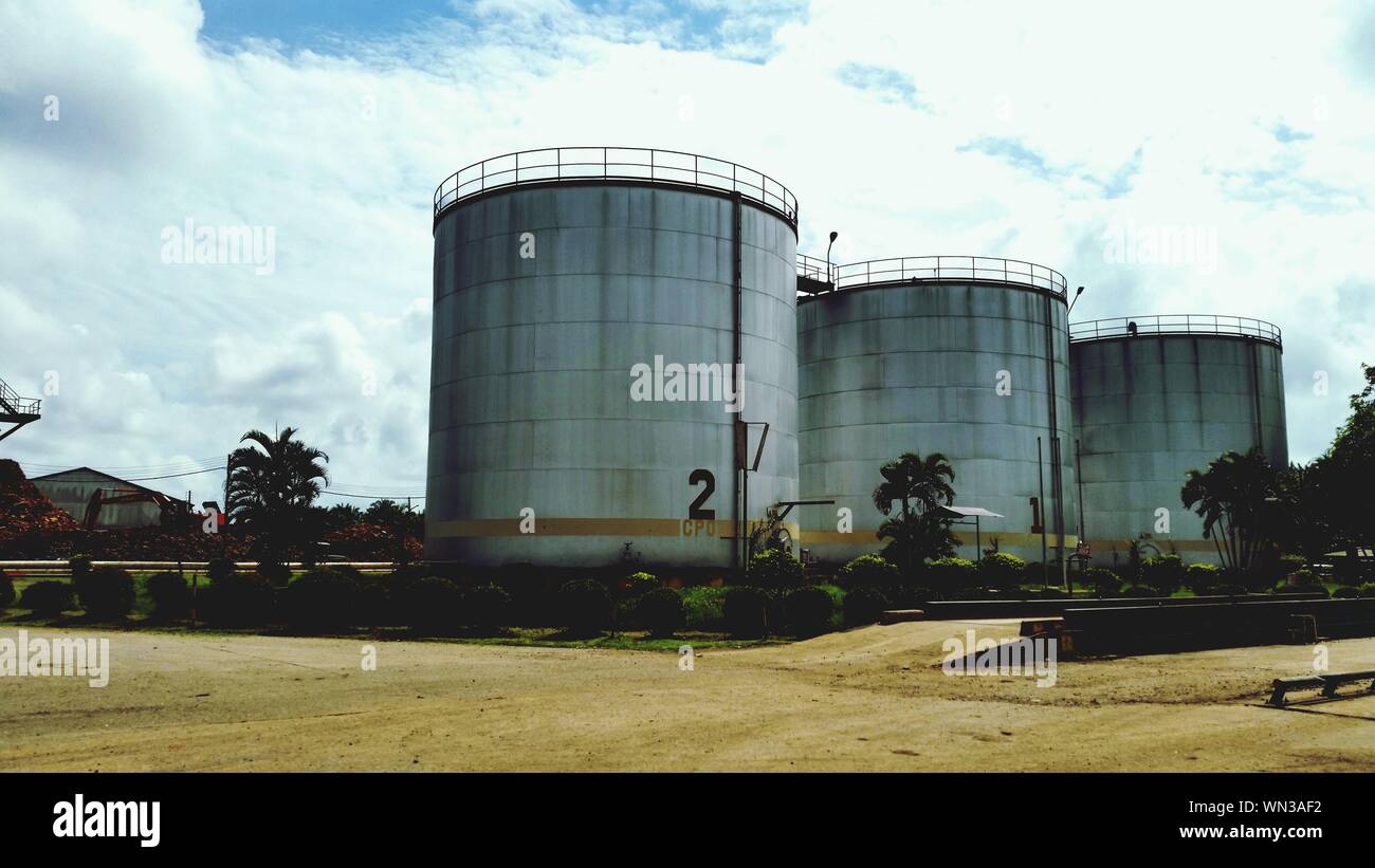 Crude Oil Storage Tank Against Cloudy Sky Stock Photo