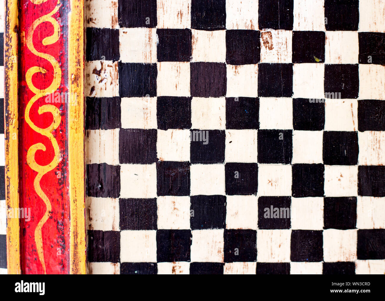 Cabinet doors given a decorative paint job with black and white checks and yellow and red borders. Stock Photo