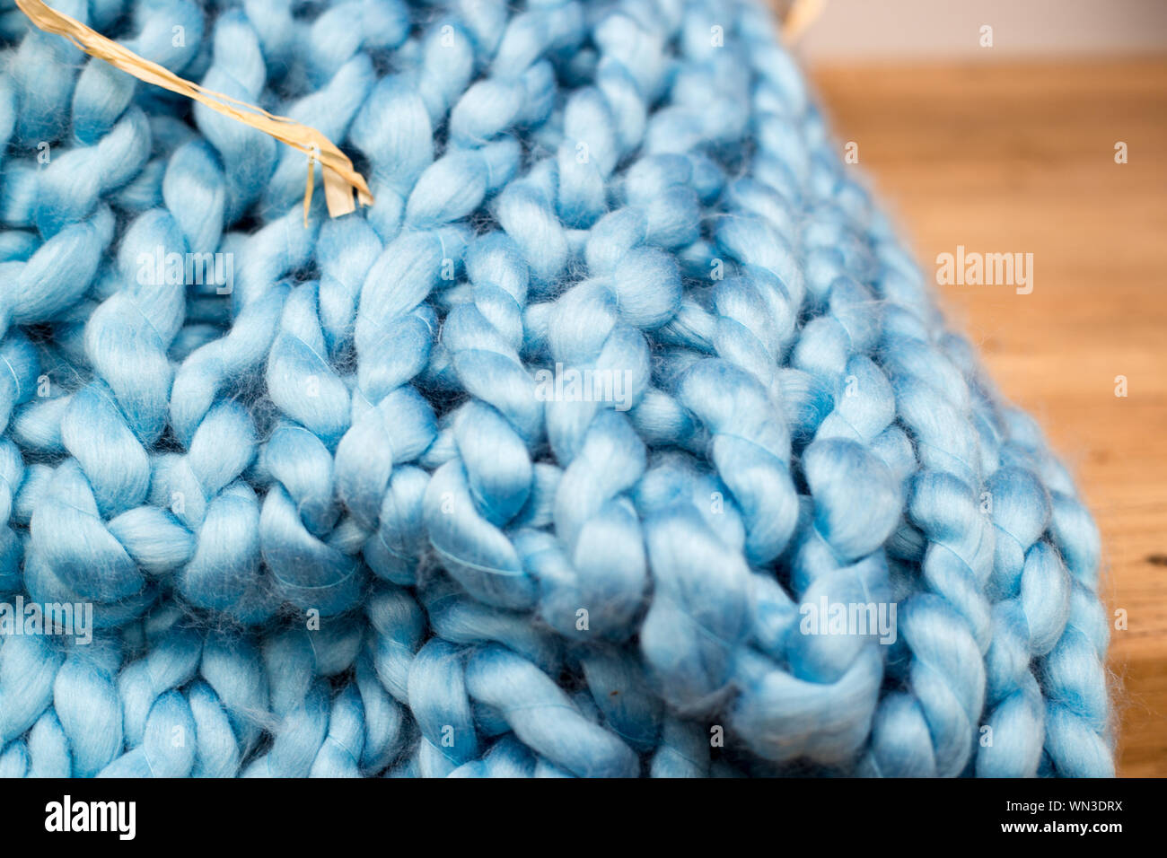 Blue knitted synthetic fibres make a bulky, chunky, handmade, throw rug Stock Photo