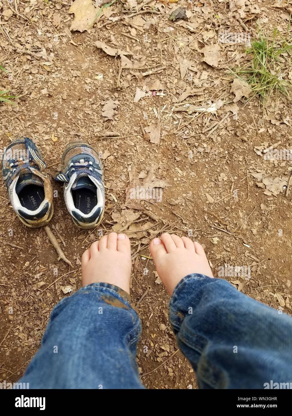 Low Angle View Of Barefoot Child By Dirt Shoes Stock Photo