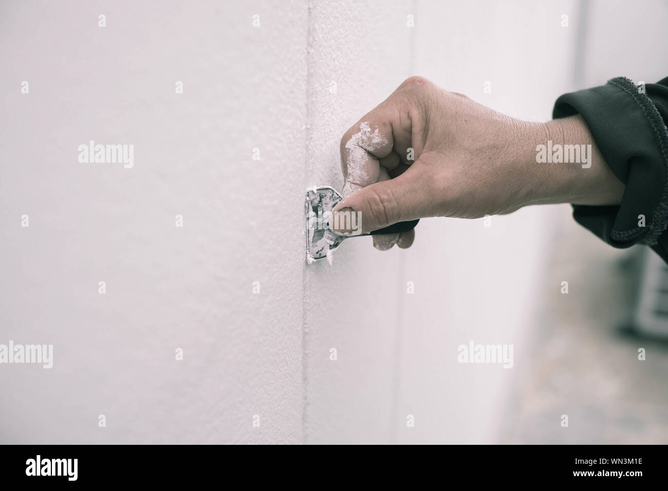 Cropped Image Of House Painter Removing Paint From Wall Stock Photo